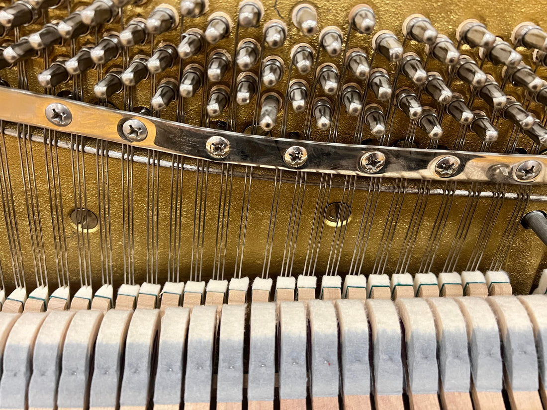 A thumbnail photo for a youtube video titled "In the shop: Restringing Process." Brigham and one of his technicians stand side by side over a piano in the process of being restored